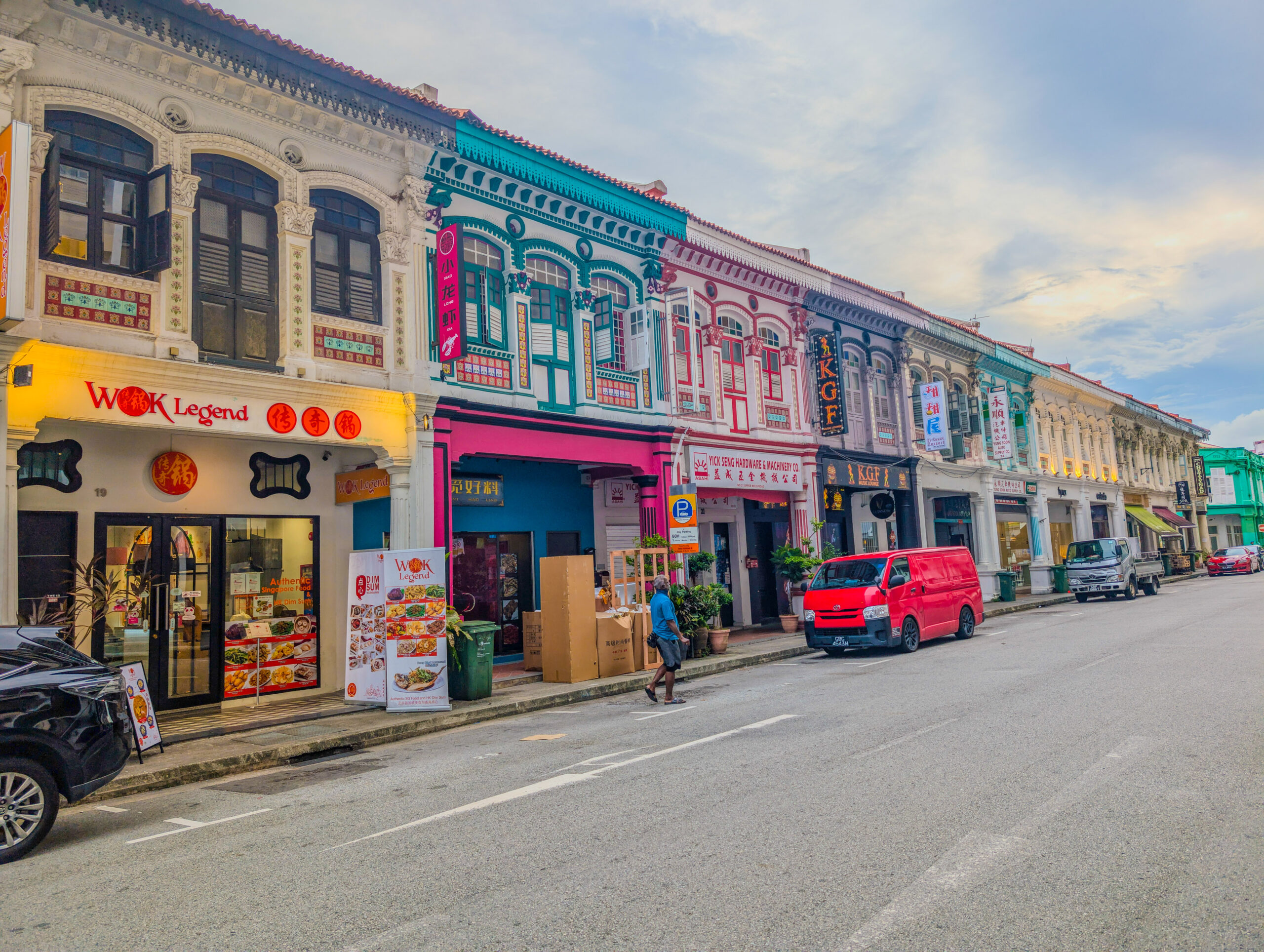 A vibrant row of colorful heritage shophouses with ornate facades, housing restaurants and shops along a street in Singapore’s Chinatown.