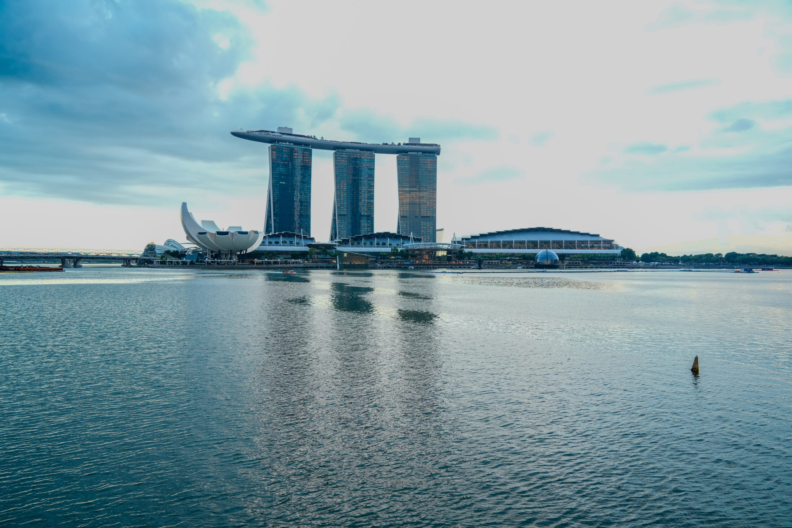 Spectacular view of the Marina Bay Sands hotel and Singapore city skyline with reflections on the water at dusk.