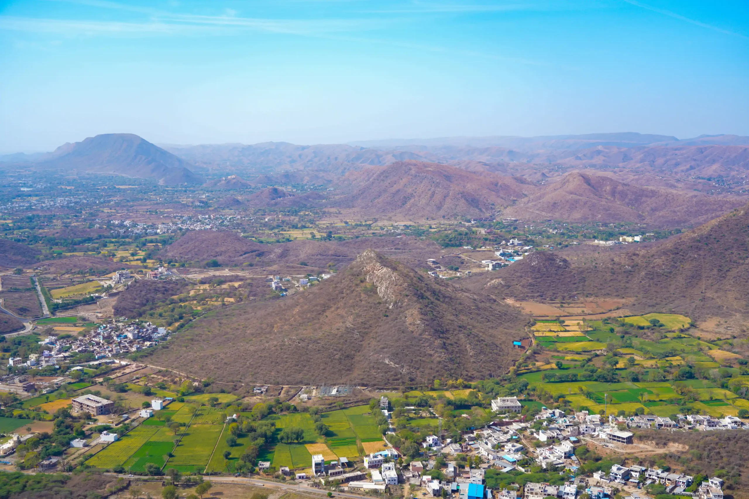 Aerial view of arid hills and patchwork green fields near Udaipur in the Aravalli highlands