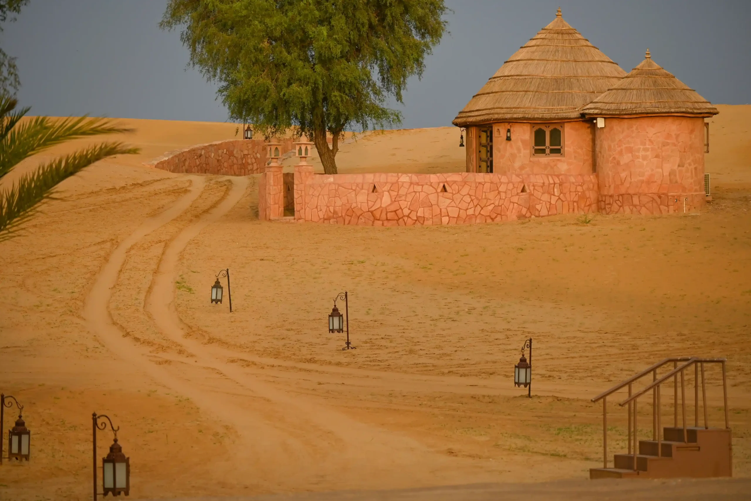 Luxury thatched desert huts and lantern-lit path at Khimsar Sand Dunes resort, Rajasthan