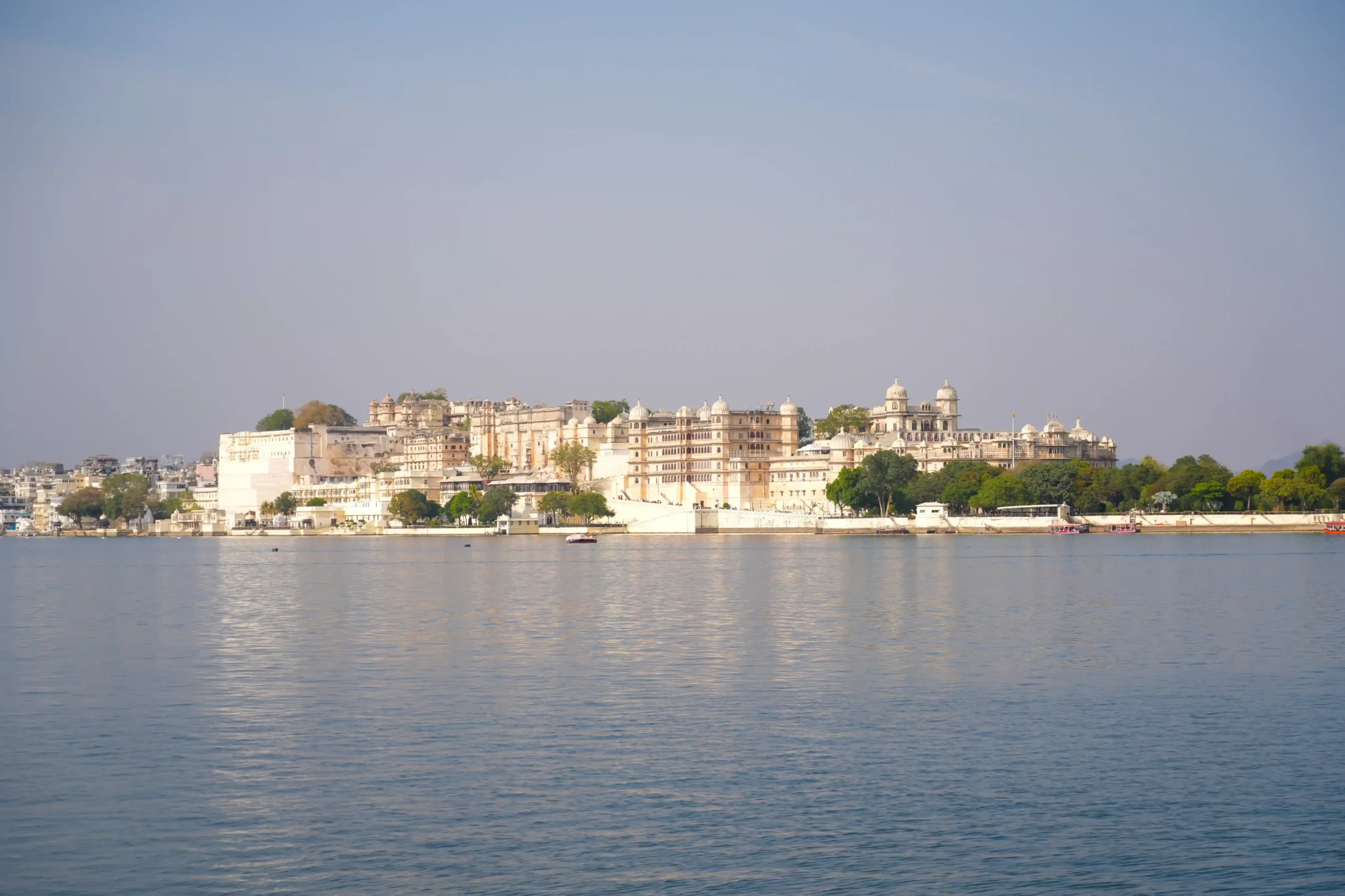 Panoramic view of Udaipur City Palace from Lake Pichola with domes and waterfront walls