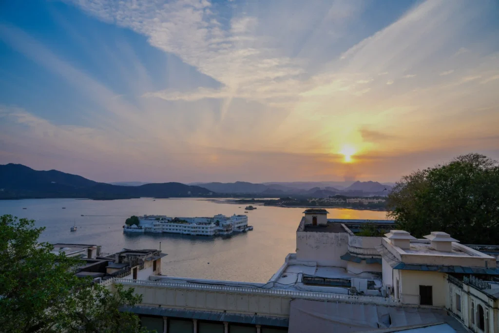 Sunset over Lake Pichola in Udaipur with Taj Lake Palace floating on the water and Aravalli hills in the background