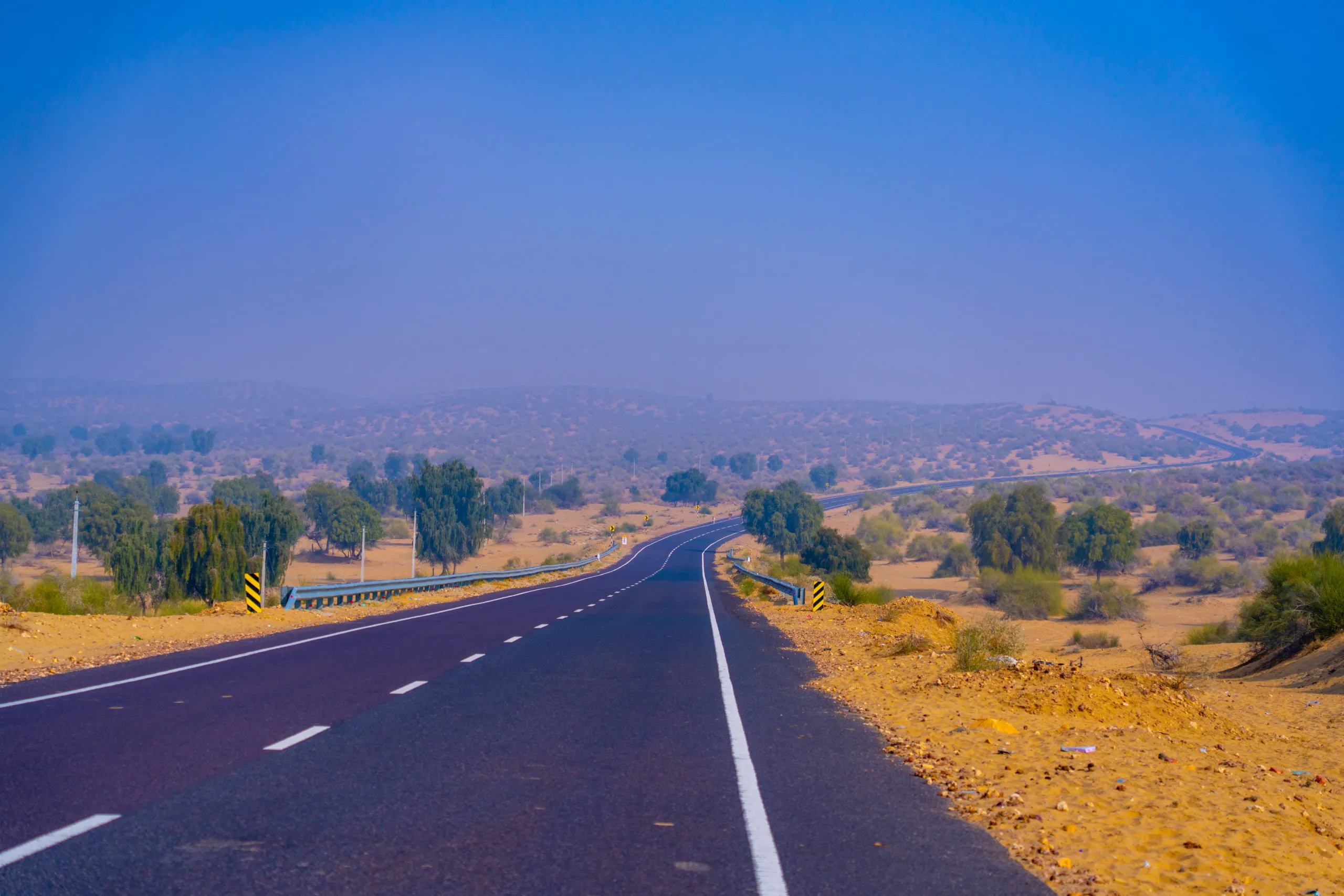 Scenic winding highway passing through arid Thar Desert land near Jaisalmer Rajasthan