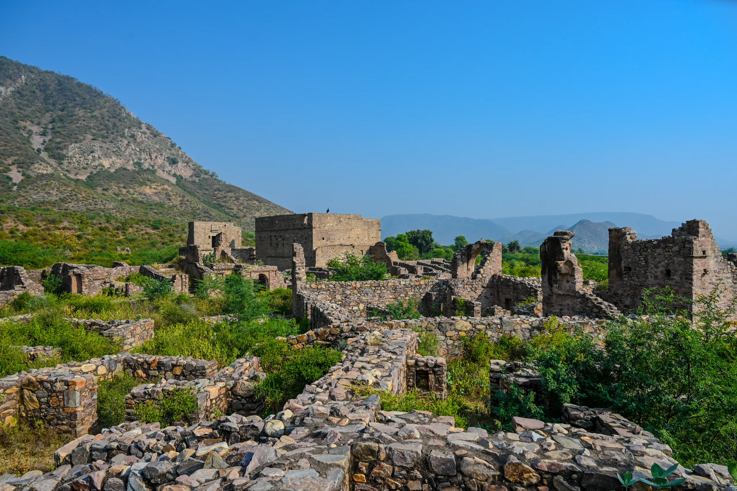 Fort ruins and old stone buildings at Bhangarh with distant hills in Alwar Rajasthan