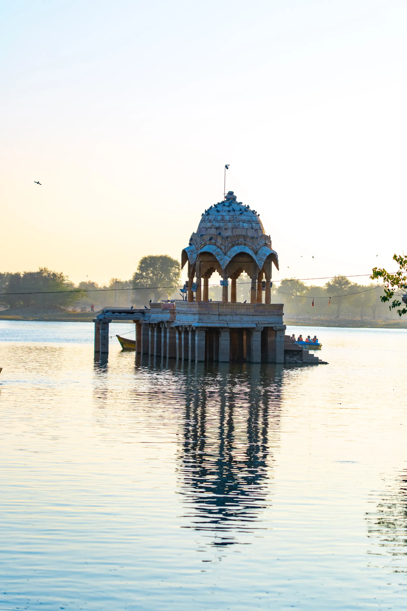 Stone pavilion reflected in Gadisar Lake at sunset in Jaisalmer Rajasthan