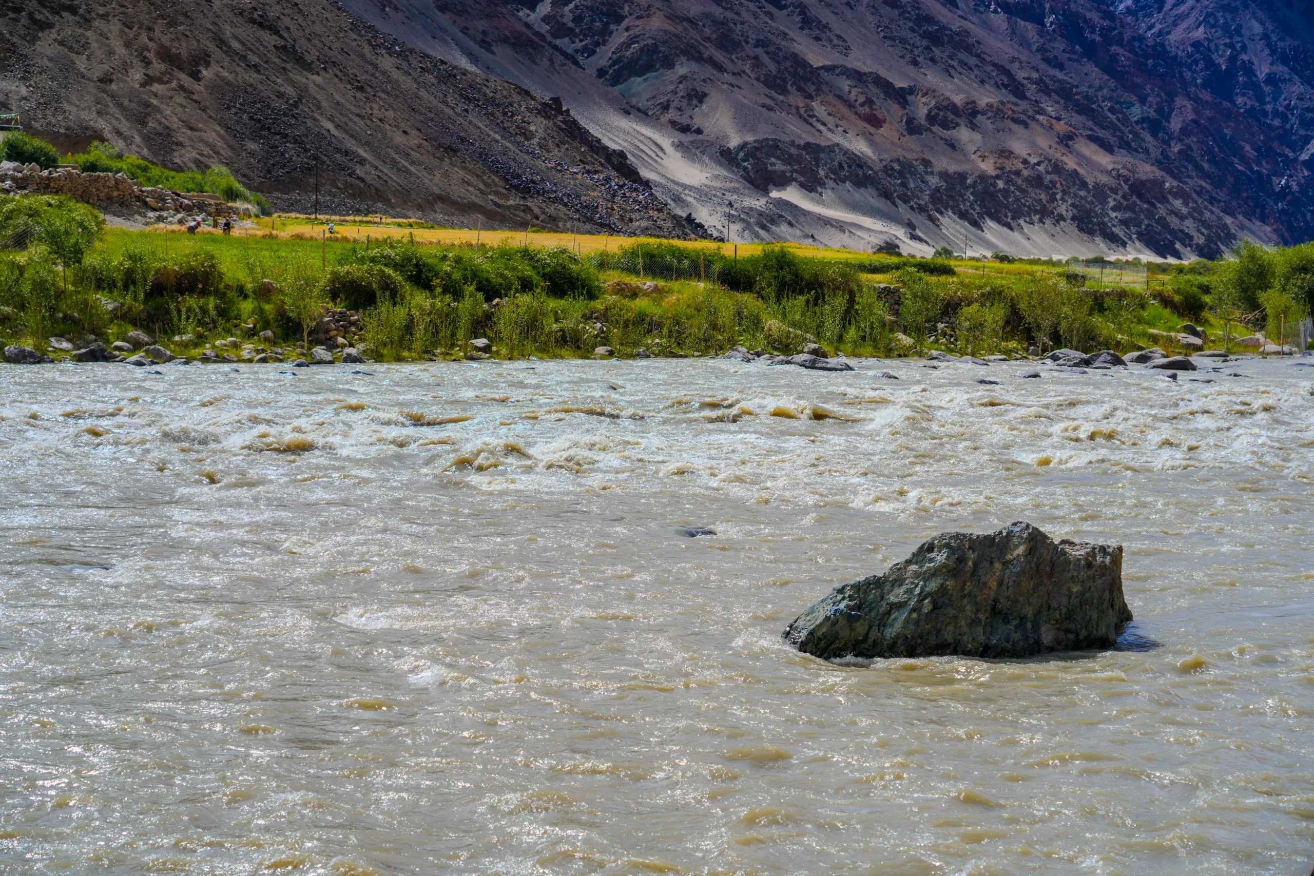 Indus River flowing past rocks with mountains in the Ladakh backdrop