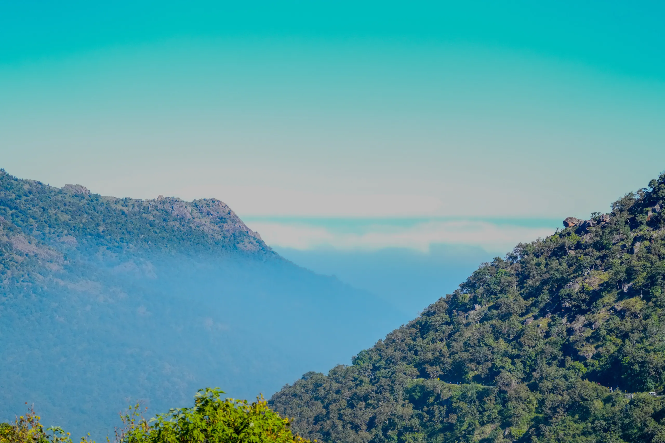 Misty valley between green hills in Ooty with soft blue layers in the distance