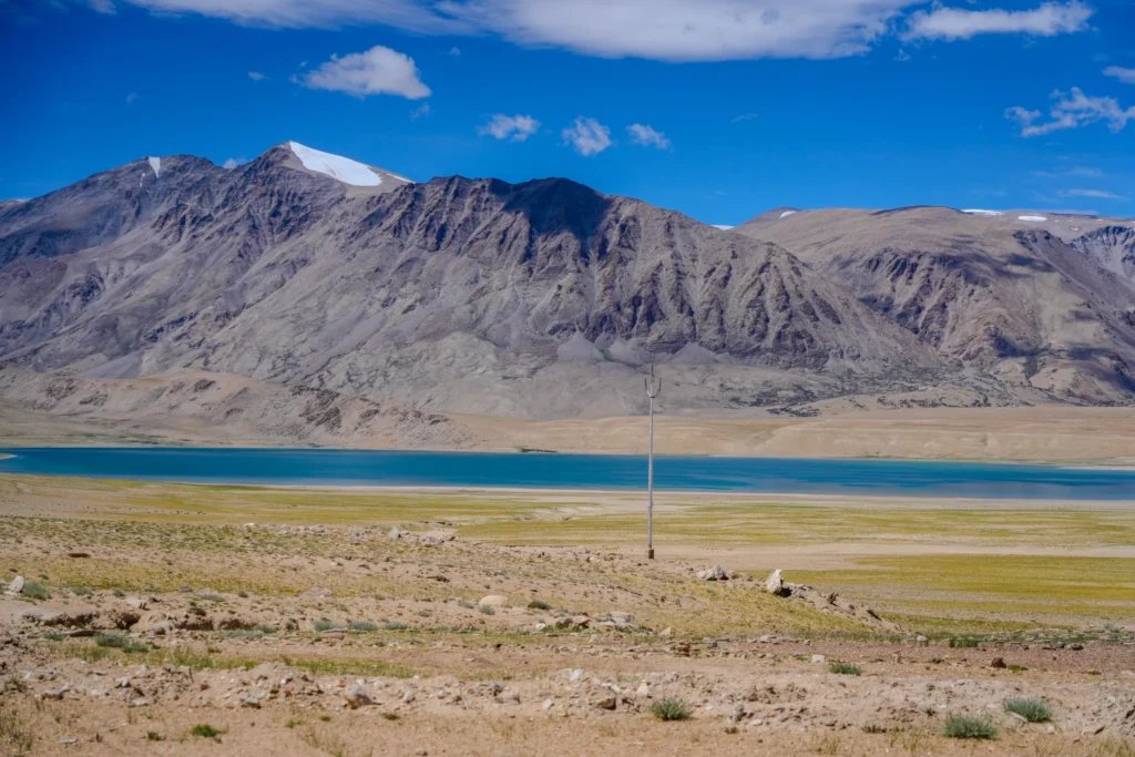 Tso Moriri Lake in Ladakh with calm blue water and snow-peaked mountains under a bright sky
